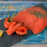 Graved-Sockeye-Lachs aus Wildlachs mit Gewürzen auf Schieferplatte angerichtet.